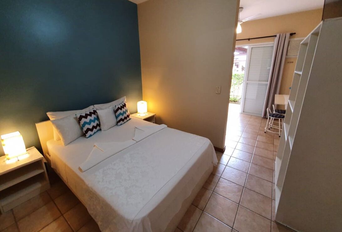 A bedroom with a bed, nightstands, and a view of a balcony.