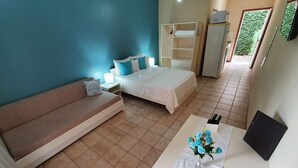 Een slaapkamer met een bed, een bank, een bureau met een bloevas en een kledingkast.
