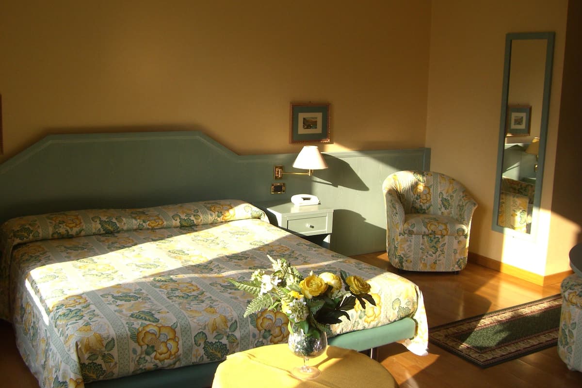 A bedroom with a bed, a chair, a desk, and a mirror.
