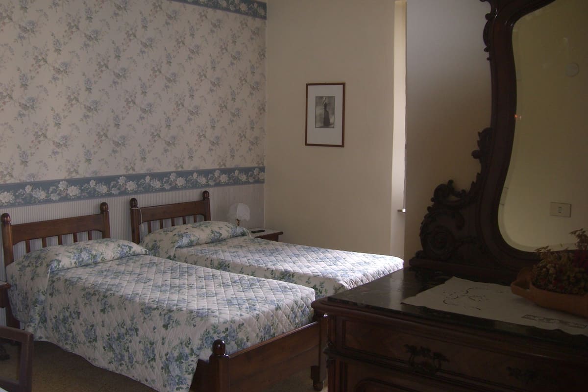 A bedroom with two wooden beds, a dresser, a mirror, and a framed picture on the wall.