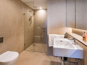 Un bagno moderno con doccia vetrata, lavandino bianco e water.