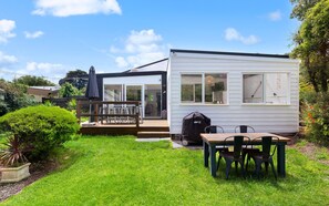 Enjoy a peaceful stay in this cozy home surrounded by a lush garden and patio area with outdoor seating and barbecue grill.