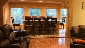 A cozy cabin interior with a dining area, leather sofas, and large windows. - Fun Seekers Getaway!!!! (Hot Springs)