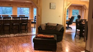 A spacious living room with a wooden floor, a black sofa, and a ceiling fan. - Fun Seekers Getaway!!!! (Hot Springs)