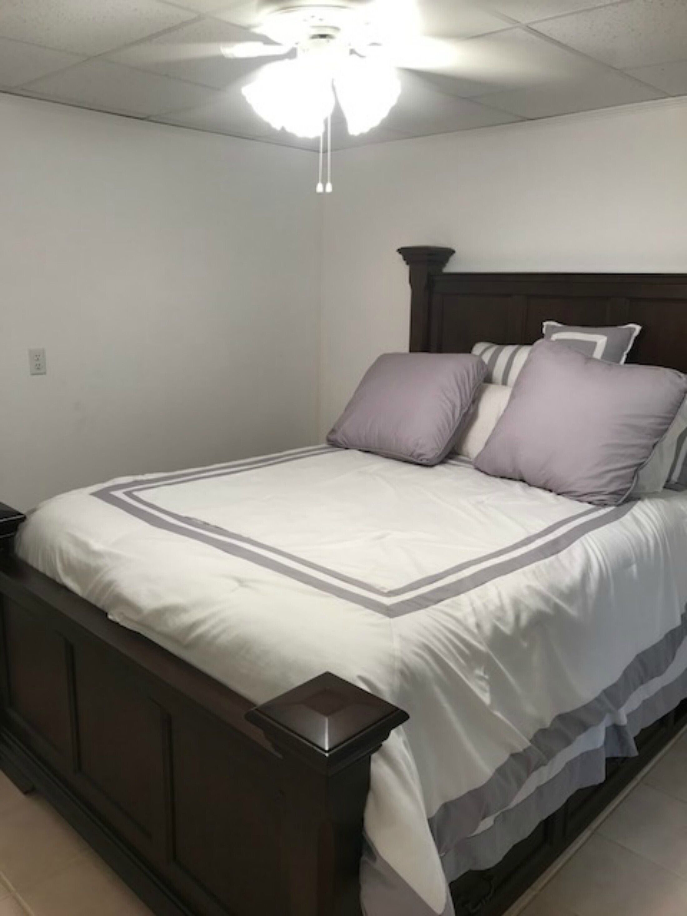 Un dormitorio con cama, mesita de noche y ventilador de techo.
