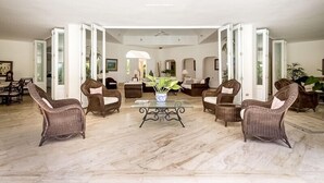 A spacious living room with a marble floor, wicker furniture, and a central coffee table. - Casa de Campo, Beautiful Villa with Pool Next to Golf Course and Beach/Sleeps 8 (La Romana)