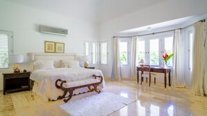 A spacious bedroom with a large bed, bedside tables, a desk, and a chair. - Casa de Campo, Beautiful Villa with Pool Next to Golf Course and Beach/Sleeps 8 (La Romana)