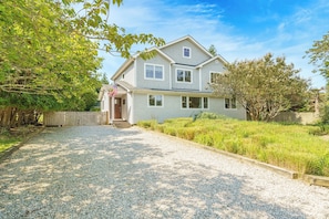 A two-story house with a gravel driveway and a wooden fence.