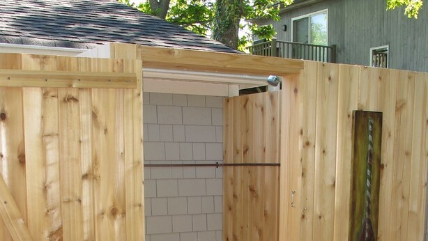 A wooden shed with a door open, revealing a brick wall inside.