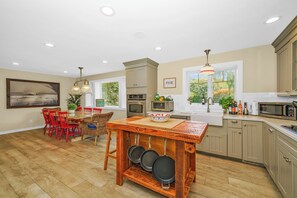 A modern kitchen with wooden flooring, a dining area with red chairs, and built-in appliances.