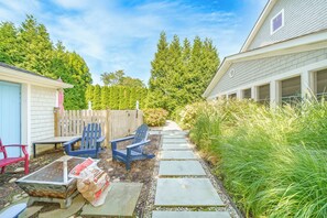 Een achtertuin met een houten terras, buitenmeubels en een pad naar een huis.