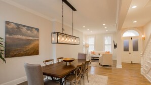 A dining area with a wooden table, chairs, and a hanging light fixture.