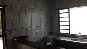 A kitchen with tiled walls, a window, and a sink.
