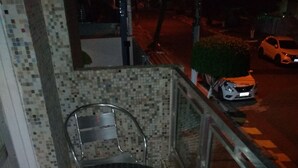 A balcony with a metal table and two chairs, a tiled wall, and a view of the street with parked cars. - Sleeps 6 people, I love this place. (Jardim Praiano)