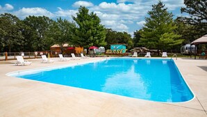 A swimming pool with lounge chairs, a 'Sunset' sign, and trees in the background. - Wilderness Retreat Cabin- Lg Game Room, Private Hot Tub; 1 Mile to Thunder Ridge (Ridgedale)