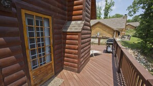 A wooden cabin with a deck, a door with glass panels, and a small outdoor grill area. - Wilderness Retreat Cabin- Lg Game Room, Private Hot Tub; 1 Mile to Thunder Ridge (Ridgedale)