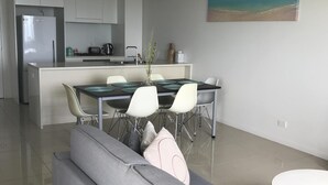 A modern kitchen with white cabinets, a dining area with a glass table, and a grey sofa. - Views of Darwin Harbor (Darwin City)
