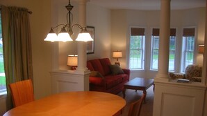 Un coin repas avec une table et des chaises en bois, un canapé rouge et une petite table avec une lampe.