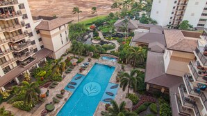 A resort with a central swimming pool, multiple balconies, and a view of the beach.