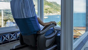 Een kamer met uitzicht op zee, een massagestoel en een betegelde vloer.