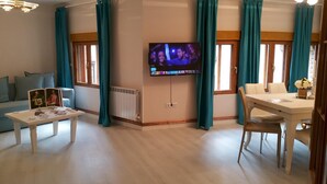 Ett vardagsrum med TV, soffa, soffbord och en matplats.