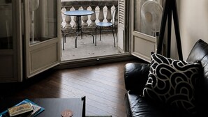 Ein Zimmer mit Balkon, Tisch, Stuhl, Sofa und Lampe.
