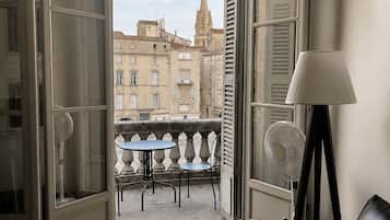 A room with a balcony, a table, a chair, a sofa, and a lamp.