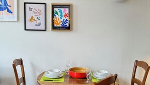 Zona pranzo con un tavolo rotondo in legno, quattro sedie di legno con sedili in vimini e una lampada a parete.