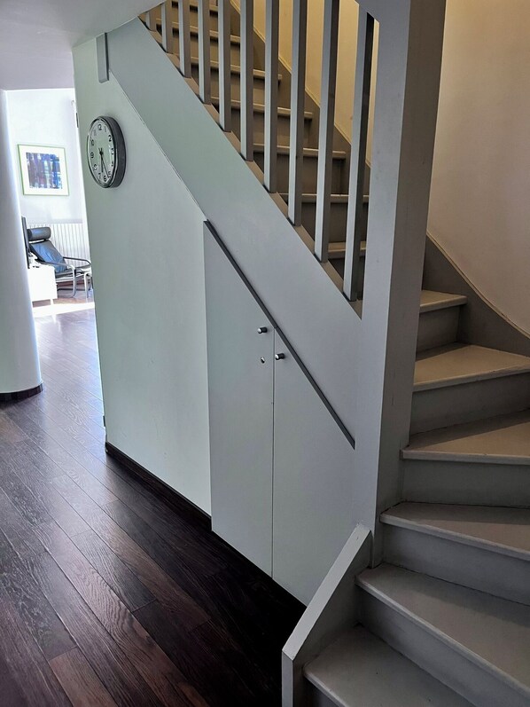 A staircase with a handrail, a clock on the wall, and a door leading to another room. - Stylish, modern apartment in the historic centre of Montpellier. (Montpellier)