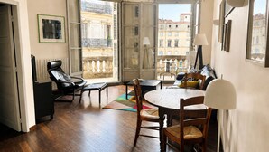 Ein modernes Wohnzimmer mit Balkon, Holzboden und einem Essbereich mit Tisch und Stühlen.
