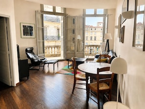 A modern living room with a balcony, wooden flooring, and a dining area with a table and chairs. - Stylish, modern apartment in the historic centre of Montpellier. (Montpellier)