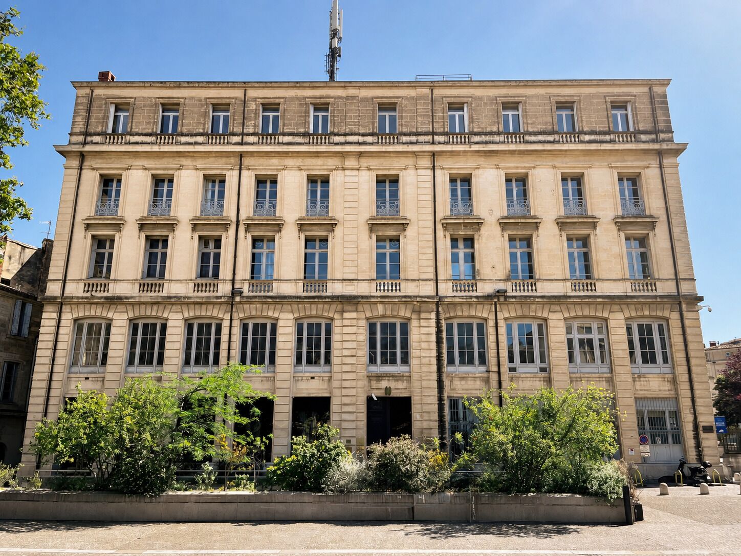 Un grand immeuble à plusieurs étages, doté d’une façade symétrique, de nombreuses fenêtres et d’une entrée centrale.
