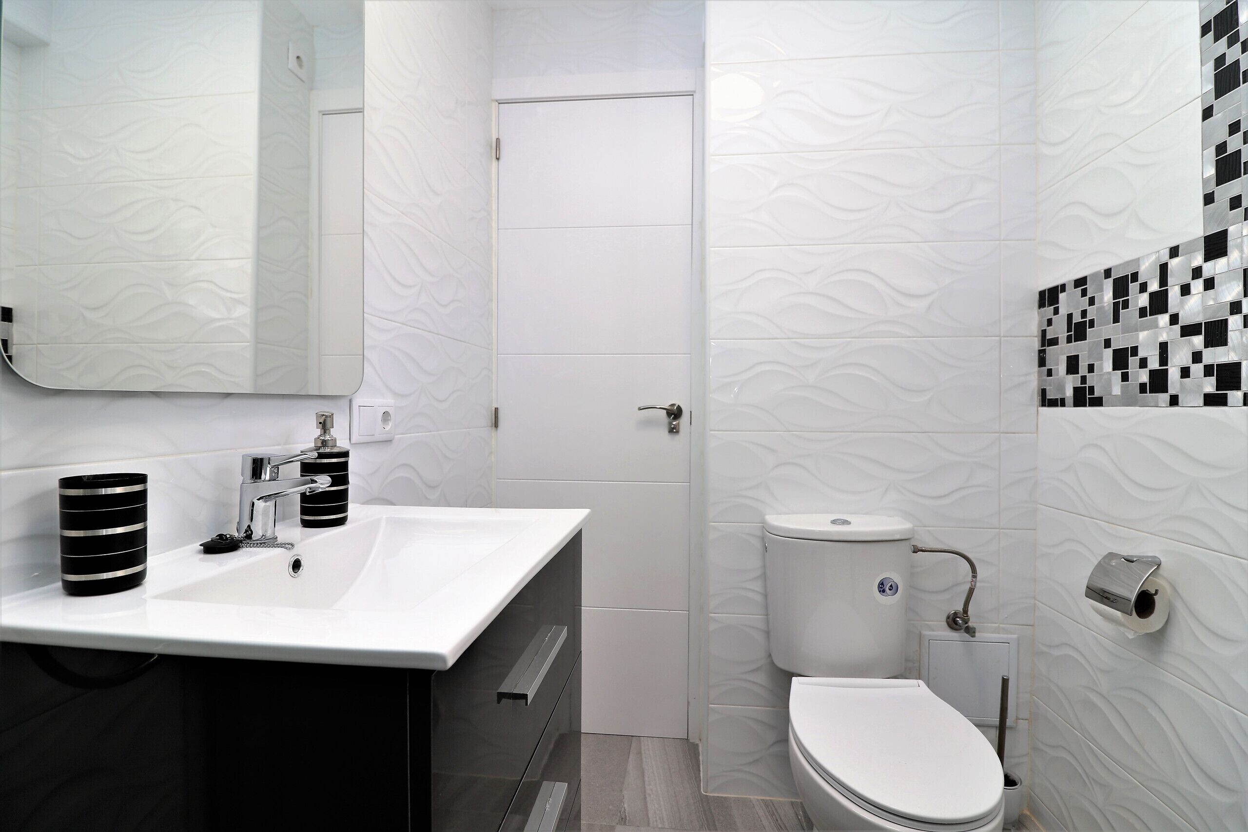 A bathroom with a white sink, a toilet, and a mirror.