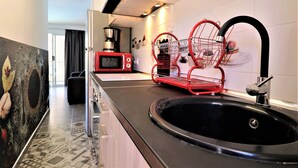 Una cucina moderna con lavello nero, porta-spezie rosso e forno a microonde rosso.