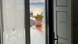 Vista des d'un balcó amb una planta en test i una porta amb adorns blaus.
