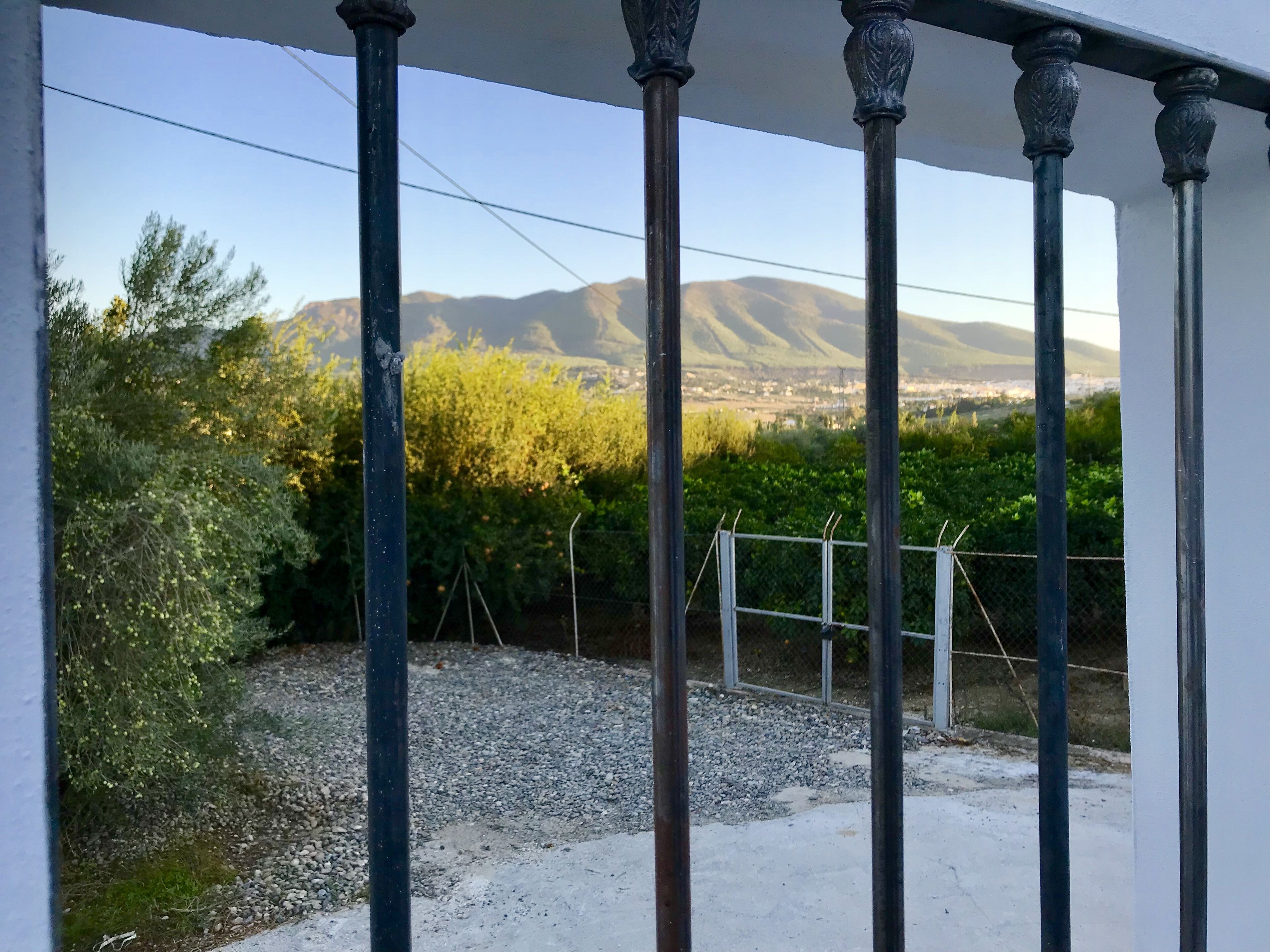 A balcony with a view of mountains and greenery.