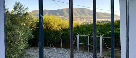 A balcony with a view of mountains and greenery.