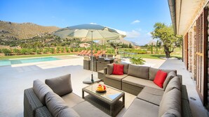 Une terrasse avec mobilier d’extérieur, une piscine et une vue sur le paysage environnant.