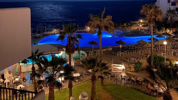 A nighttime view of a resort with a pool, palm trees, and a view of the ocean. - 2 Bedroom, 2 bathroom front line property in Cala D'or (07660 Cala D'or)
