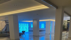 A spacious lobby with a polished marble floor, a staircase, and a seating area with a blue-lit wall. - 2 Bedroom, 2 bathroom front line property in Cala D'or (07660 Cala D'or)