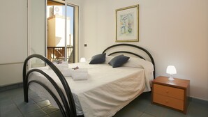 A neatly made bed with a white comforter, two pillows, and a bedside lamp on a wooden nightstand. - Apartment 10 meters from the sea for 4 people in the center, free wi-fi (Marina di Ragusa)