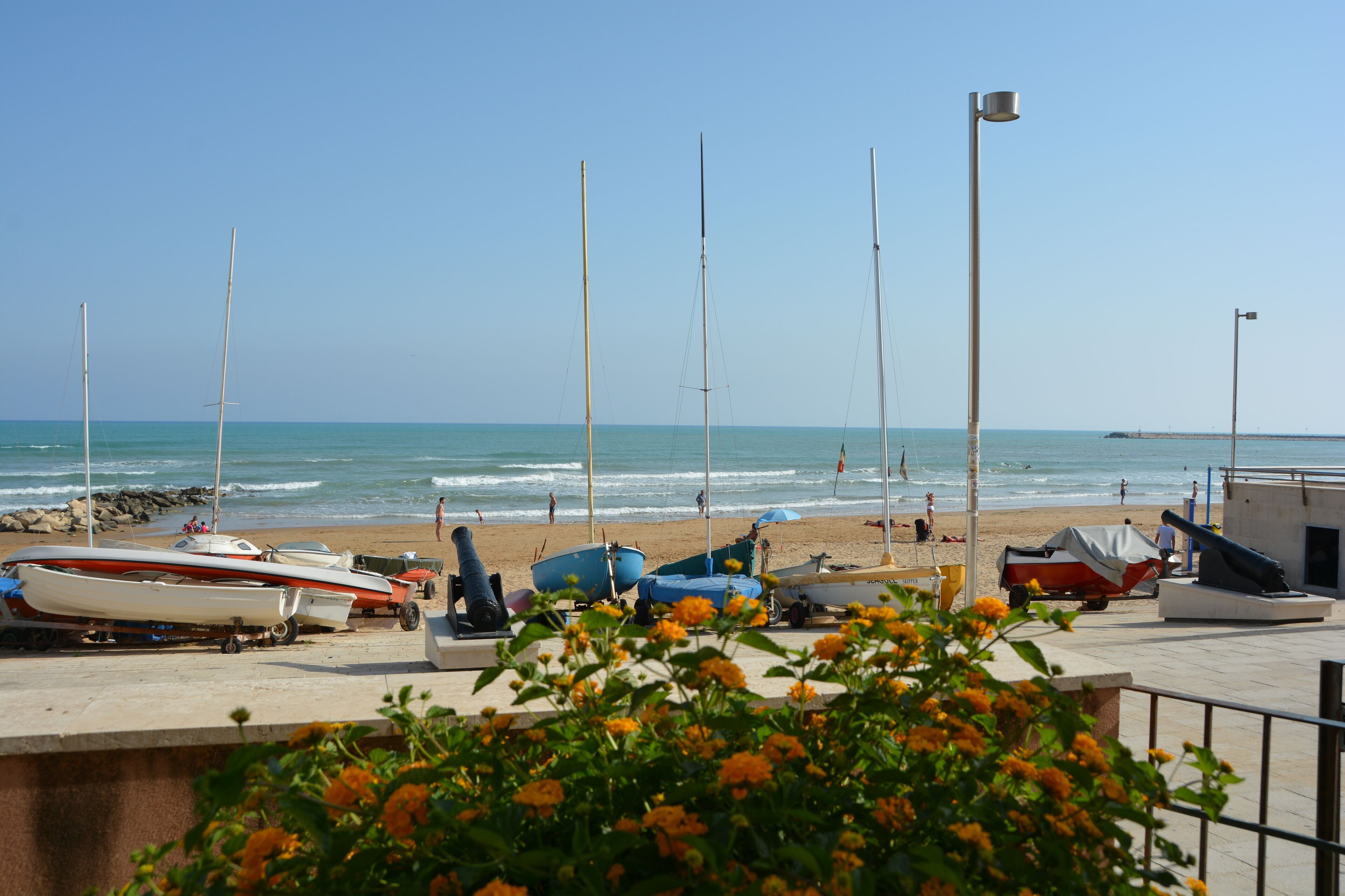 A beachside boat storage area with several boats, a pier, and a clear view of the ocean.