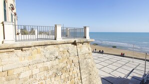 A stone wall with a metal railing overlooking a beach. - Apartment 10 meters from the sea for 4 people in the center, free wi-fi (Marina di Ragusa)
