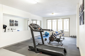 Gimnasio con cinta de correr, bicicleta estática, pelotas de ejercicio y mancuernas.