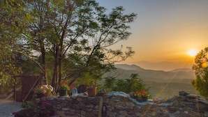 A stone wall with potted plants and a view of distant mountains during sunset. - The Old Pomegranate House - Sea view - AC - WIFI (Mirsini)