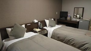 Una habitación de hotel con dos camas, un escritorio, un televisor y un espejo.