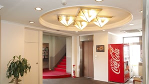 Un vestíbulo con una escalera, una máquina expendedora de Coca-Cola y una planta en maceta.