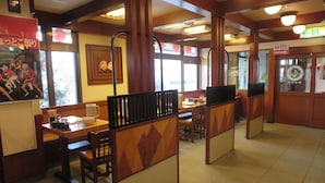 Interior de restaurante con mobiliario de madera, pisos de baldosas y estética japonesa tradicional.