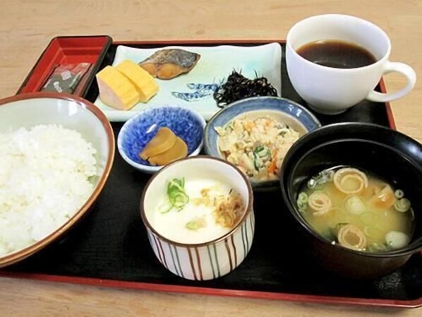 Una bandeja con diferentes platos japoneses, incluyendo arroz, sopa y una taza de té.