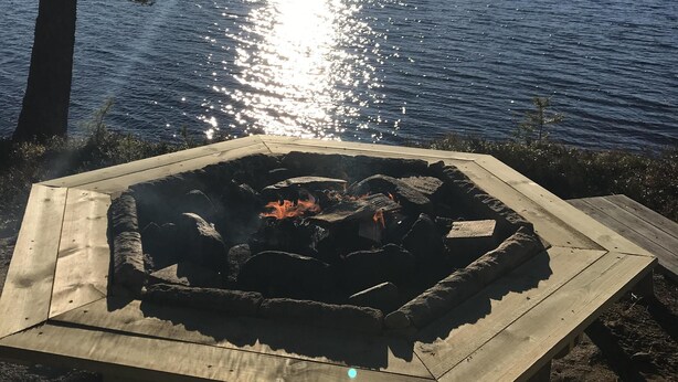 A lakeside view with a fire pit in the foreground. - Lillarmsjö-cottage, cottage with lake view. (Lillarmsjö)